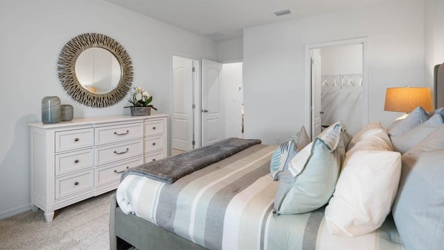 bedroom with a walk in closet, light carpet, and a closet