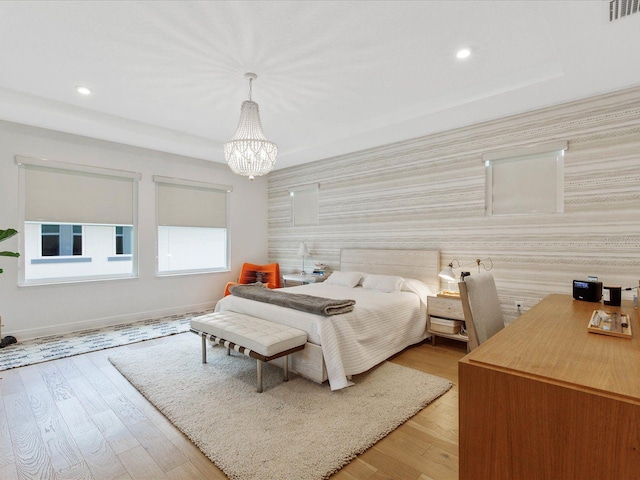 bedroom with light hardwood / wood-style flooring and a chandelier