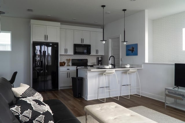 kitchen featuring kitchen peninsula, pendant lighting, white cabinetry, and black appliances