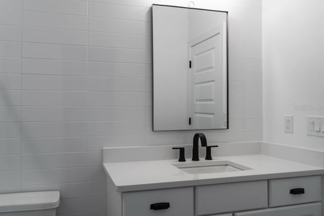 bathroom with vanity, tile walls, and toilet