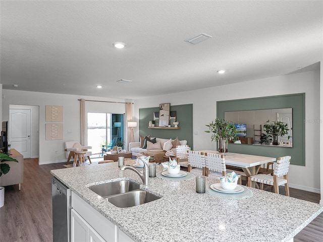 kitchen with light stone counters, stainless steel dishwasher, a kitchen island with sink, sink, and white cabinets