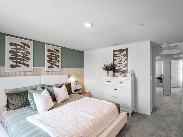 bedroom with a textured ceiling and light colored carpet