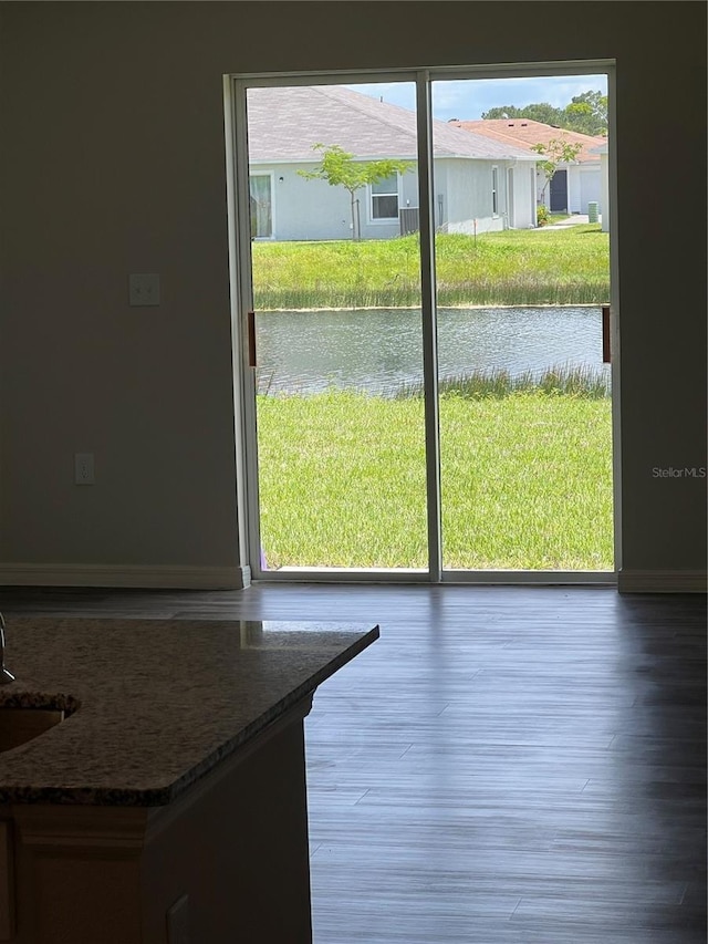 doorway with a water view, light wood-type flooring, and sink