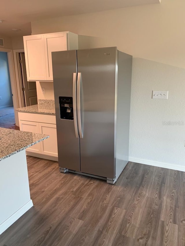 kitchen with light stone countertops, stainless steel refrigerator with ice dispenser, dark hardwood / wood-style floors, and white cabinetry