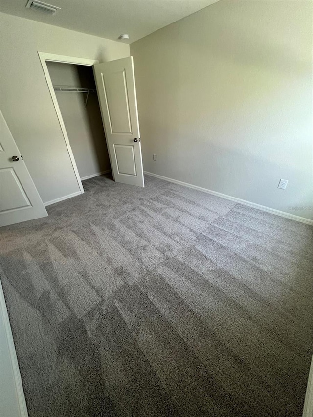 unfurnished bedroom with dark colored carpet and a closet