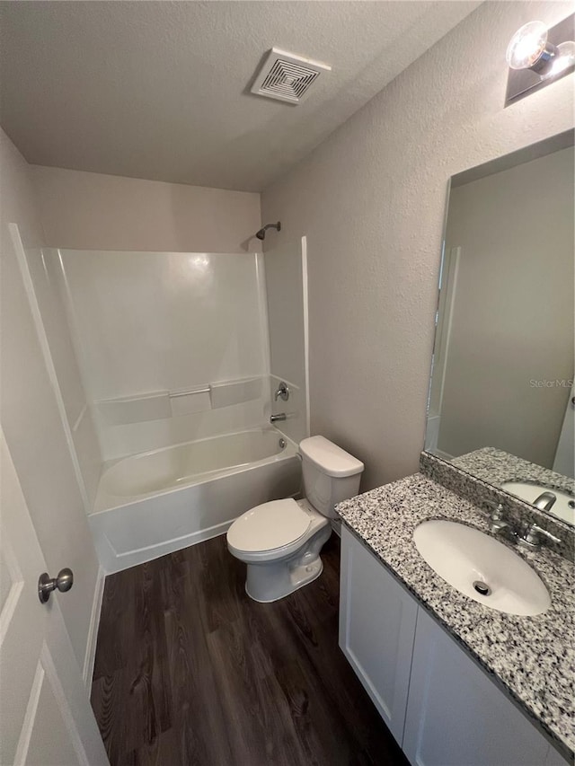 full bathroom with  shower combination, toilet, a textured ceiling, vanity, and hardwood / wood-style flooring