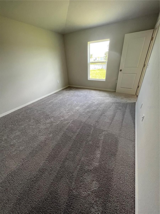 unfurnished room featuring carpet and vaulted ceiling