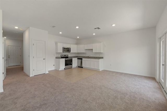 kitchen featuring stainless steel appliances, white cabinetry, light colored carpet, and sink