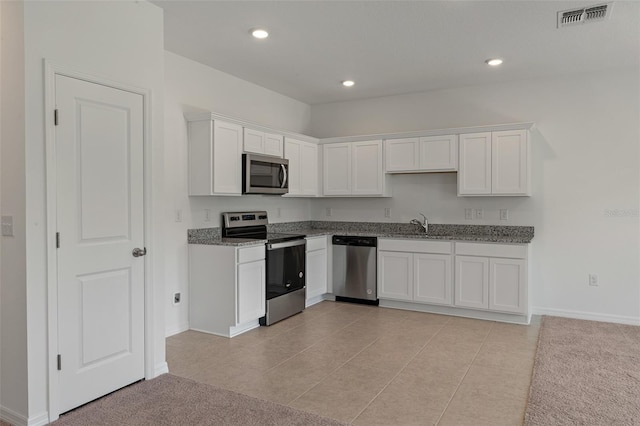 kitchen featuring white cabinets, light tile patterned floors, stainless steel appliances, and light stone counters