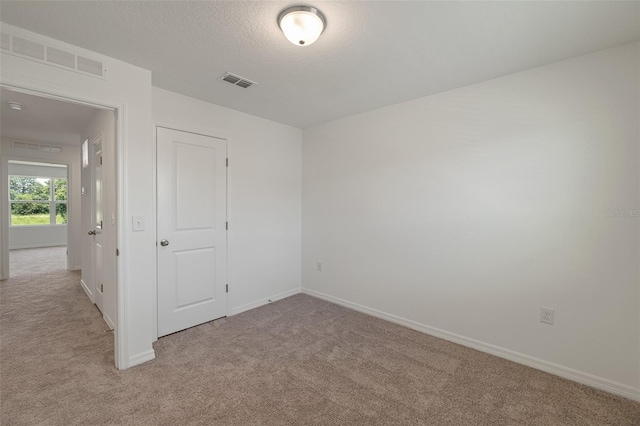 carpeted empty room with a textured ceiling