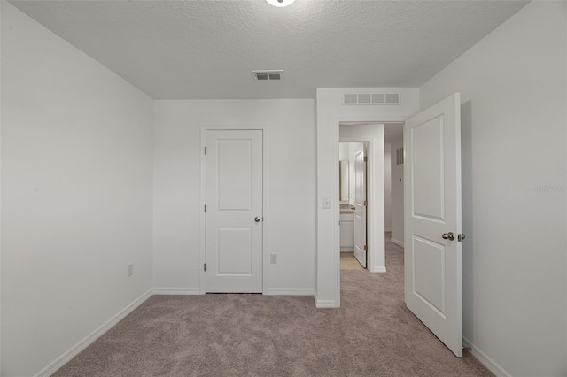 unfurnished bedroom featuring a textured ceiling and light carpet