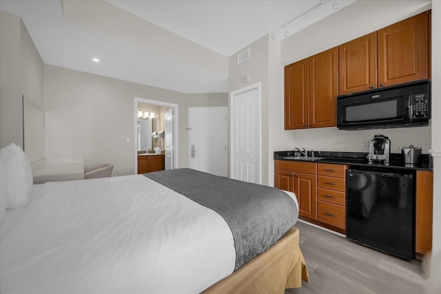 bedroom with ensuite bath, sink, and light wood-type flooring