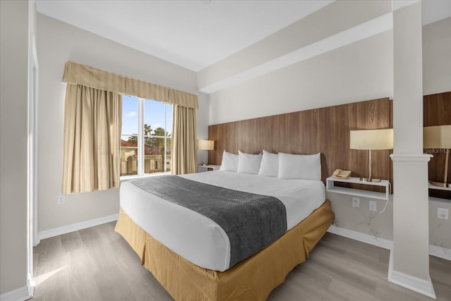 bedroom featuring decorative columns and light hardwood / wood-style flooring