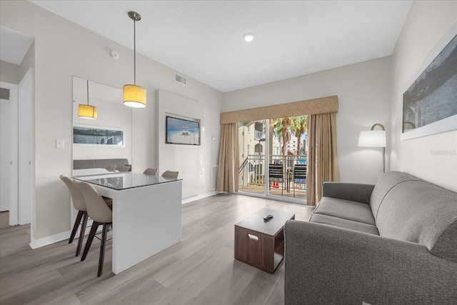 living area featuring baseboards, visible vents, and wood finished floors