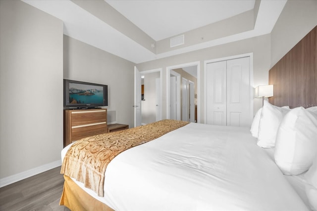 bedroom with visible vents, baseboards, wood finished floors, and a closet