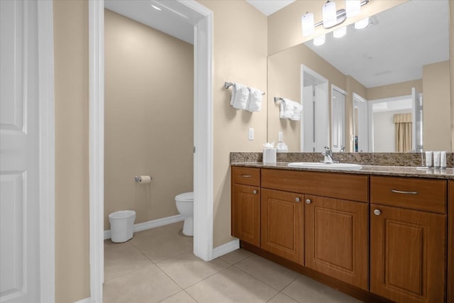 bathroom with toilet, tile patterned floors, baseboards, and vanity