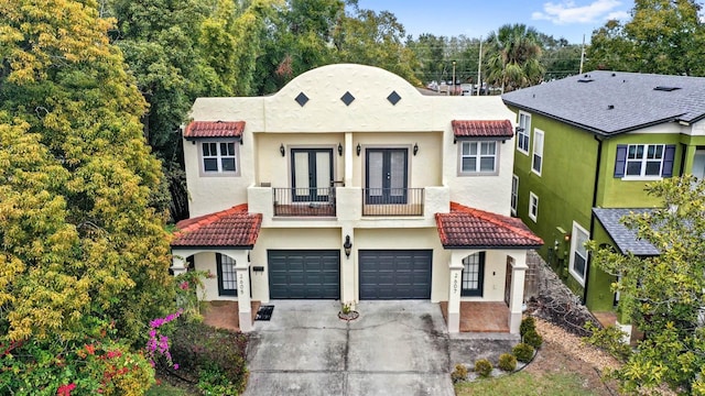 view of front facade featuring a garage, a balcony, and french doors