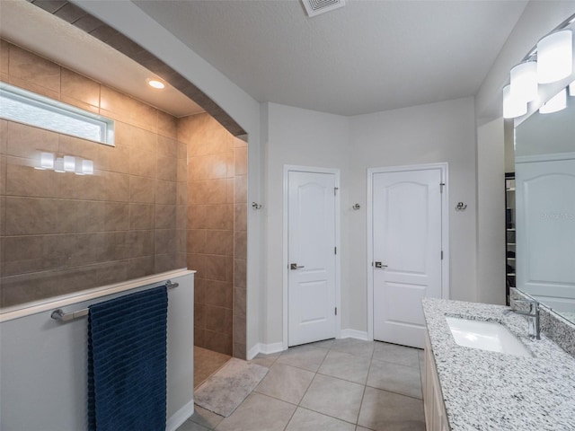 bathroom with vanity, tile patterned flooring, and tiled shower