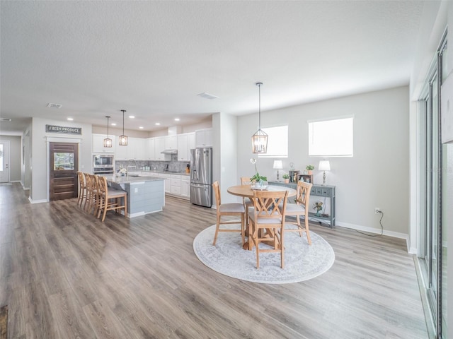 dining room with light hardwood / wood-style floors and a textured ceiling