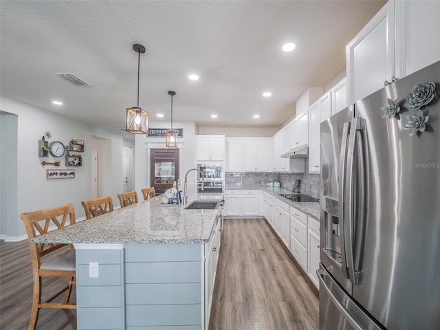 kitchen featuring sink, a large island with sink, a kitchen breakfast bar, stainless steel appliances, and white cabinets