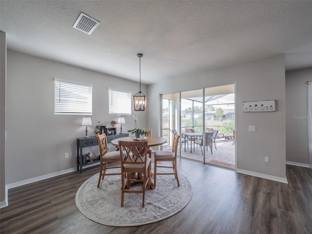 dining room featuring an inviting chandelier, plenty of natural light, dark hardwood / wood-style floors, and a textured ceiling