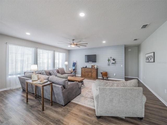 living room with ceiling fan, dark wood-type flooring, and a textured ceiling