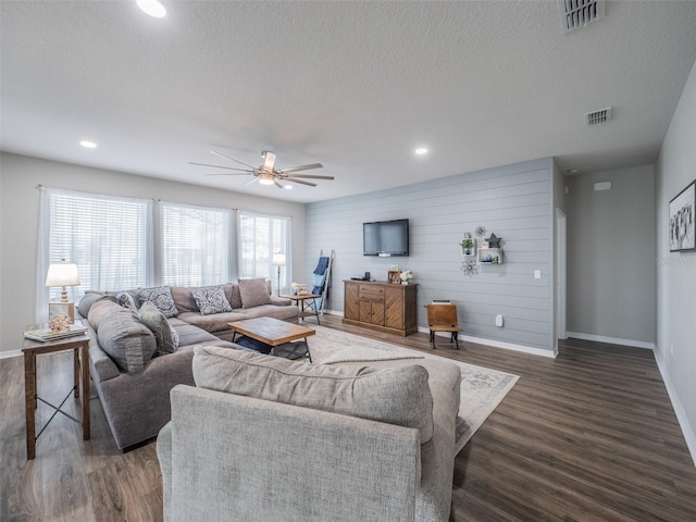 living room with ceiling fan, dark hardwood / wood-style floors, and a textured ceiling