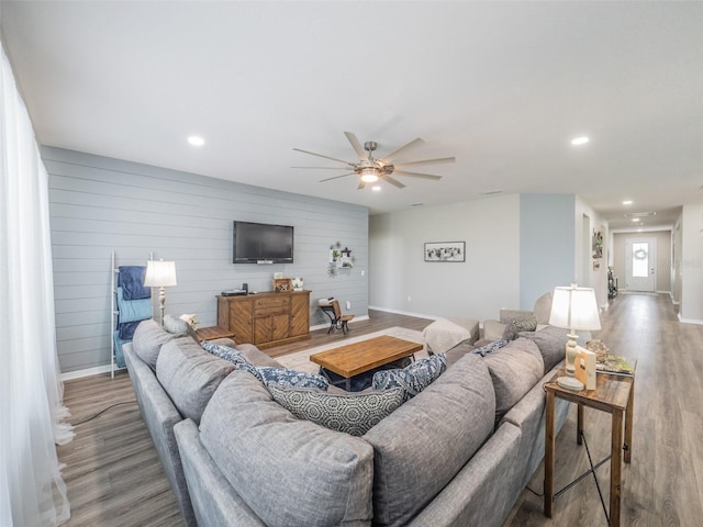 living room featuring hardwood / wood-style flooring, ceiling fan, and wooden walls