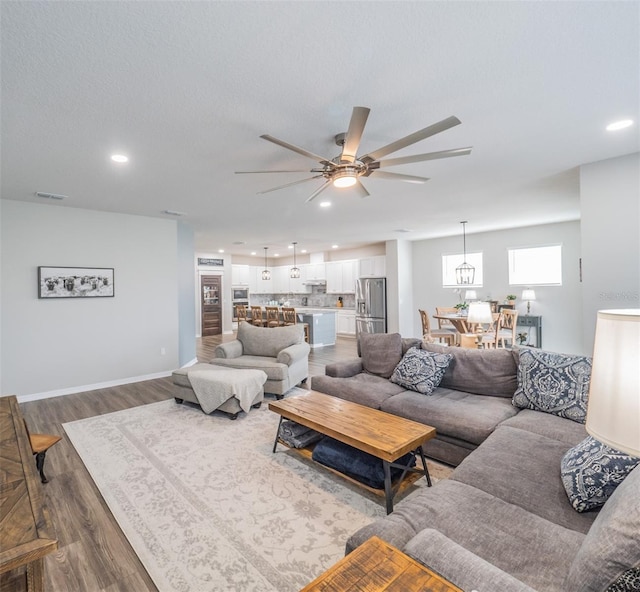 living room with hardwood / wood-style floors, a textured ceiling, and ceiling fan