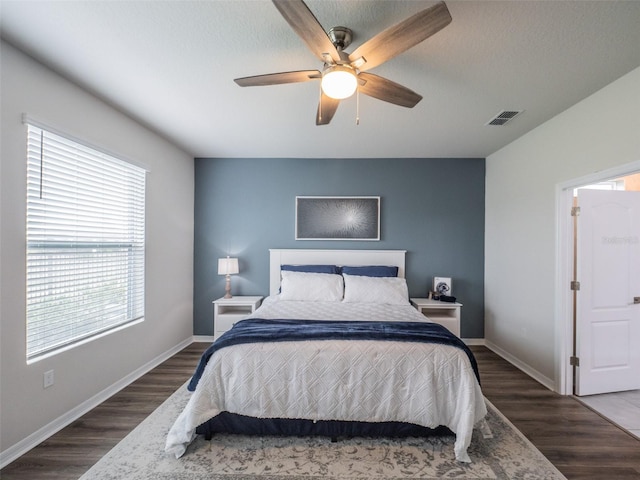 bedroom featuring dark hardwood / wood-style flooring, ceiling fan, and a textured ceiling