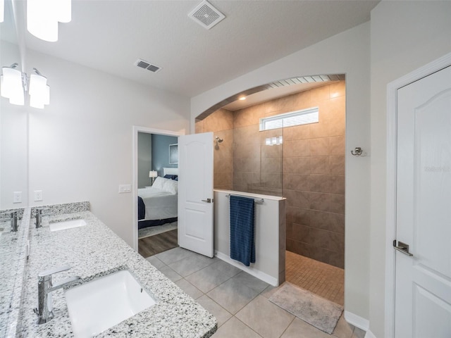 bathroom with vanity, tiled shower, and tile patterned floors