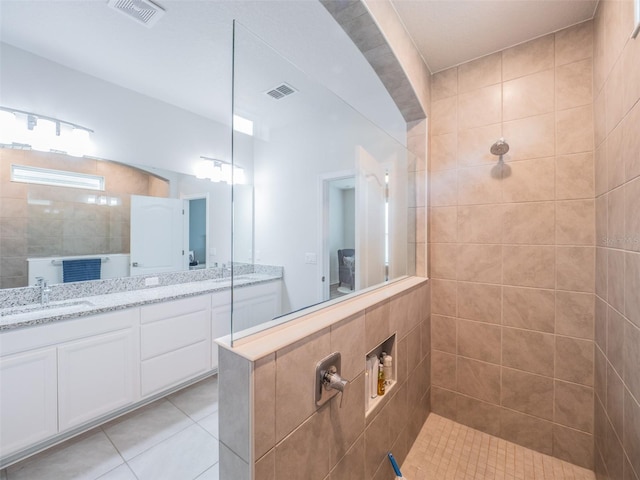 bathroom with tile patterned floors, vanity, and tiled shower