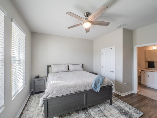 bedroom with ceiling fan, ensuite bathroom, and dark hardwood / wood-style flooring