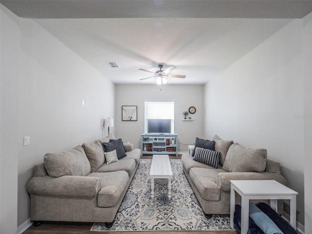 living room featuring hardwood / wood-style flooring, ceiling fan, and a textured ceiling