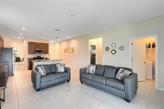 living room with washer / dryer and light tile patterned floors