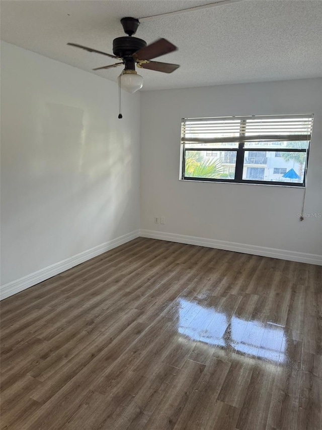 unfurnished room with ceiling fan, dark wood-type flooring, and a textured ceiling