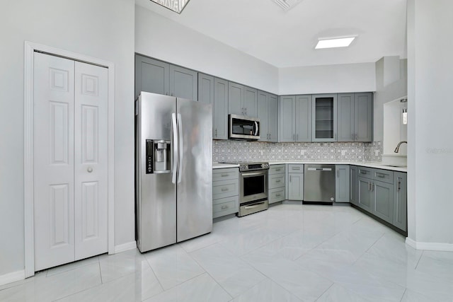 kitchen featuring stainless steel appliances, gray cabinets, sink, and decorative backsplash