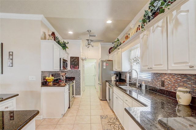 kitchen featuring appliances with stainless steel finishes, dark stone counters, sink, light tile patterned floors, and white cabinets