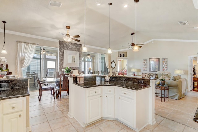 kitchen featuring white cabinets, dark stone countertops, light tile patterned floors, and hanging light fixtures