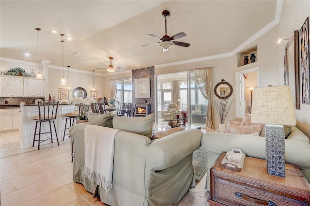 tiled living room featuring ceiling fan, a large fireplace, and ornamental molding