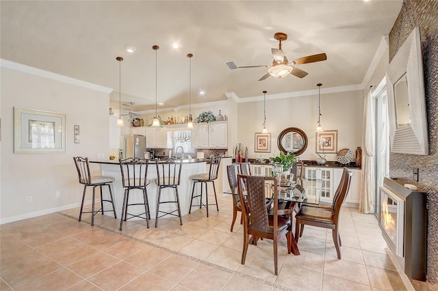 dining area featuring ceiling fan, light tile patterned flooring, and ornamental molding