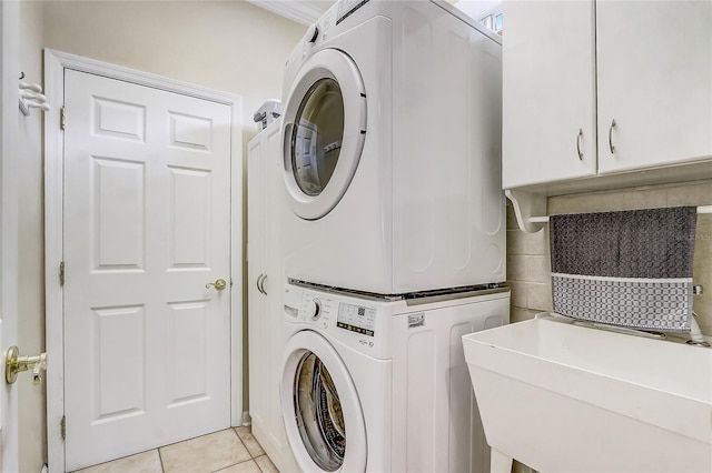 laundry area featuring sink, light tile patterned flooring, and stacked washer / drying machine