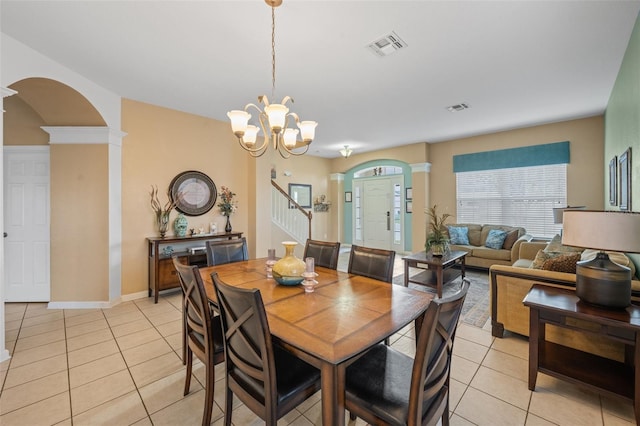 dining space with decorative columns, light tile patterned floors, and a chandelier