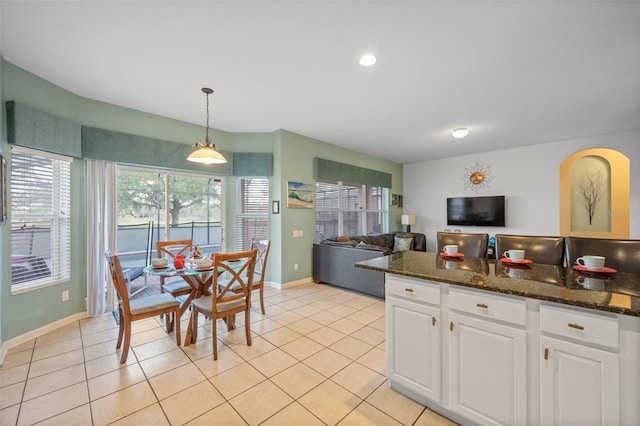 kitchen with white cabinets, pendant lighting, light tile patterned floors, and dark stone countertops