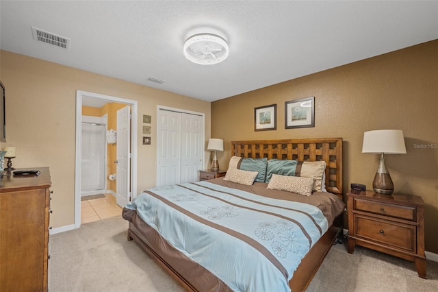 bedroom with connected bathroom, light colored carpet, and a textured ceiling