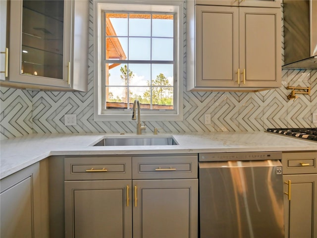 kitchen with tasteful backsplash, light stone counters, sink, dishwasher, and gray cabinets