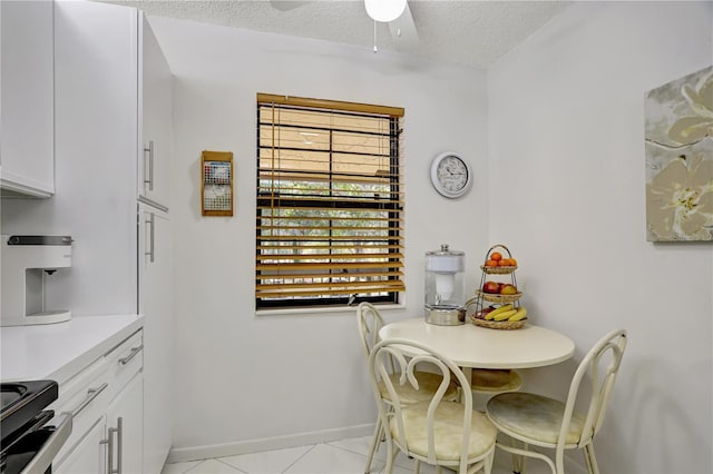 tiled dining area with a textured ceiling and ceiling fan