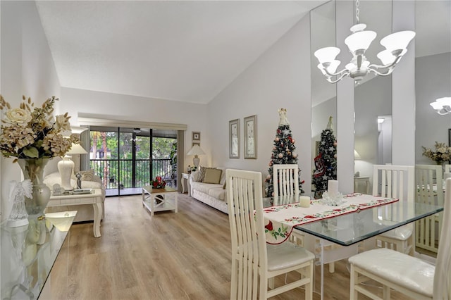 dining space featuring light wood-type flooring, high vaulted ceiling, and a chandelier