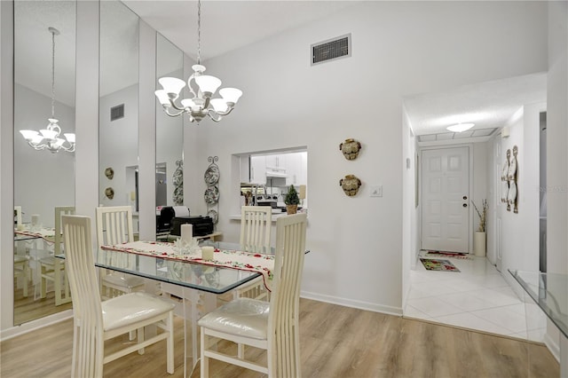 dining room featuring light hardwood / wood-style flooring, high vaulted ceiling, and an inviting chandelier