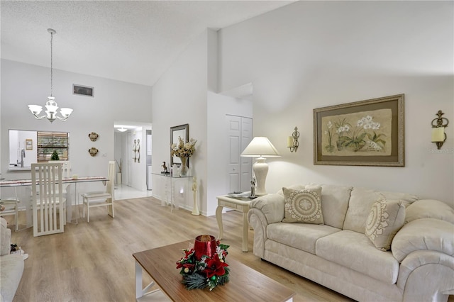 living room with hardwood / wood-style floors, high vaulted ceiling, and a notable chandelier